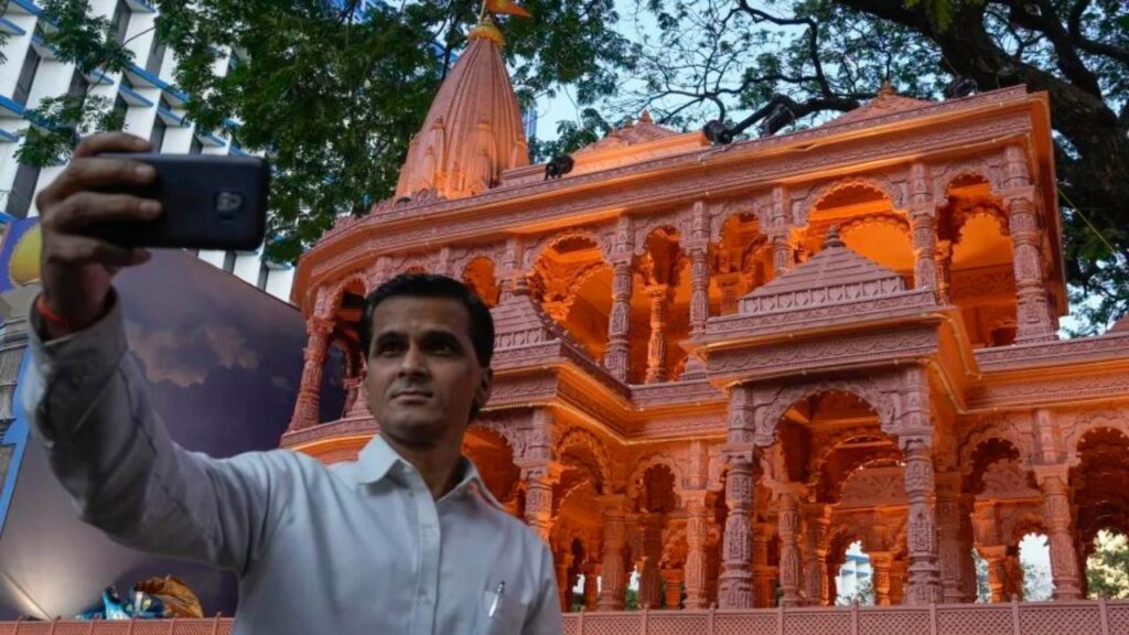 On Tuesday, January 16, 2024, in Mumbai, India, a person takes a selfie in front of a replica of the Lord Ram temple in Ayodhya, which is on display outside the Bharatiya Janata Party office, which is in power in India.