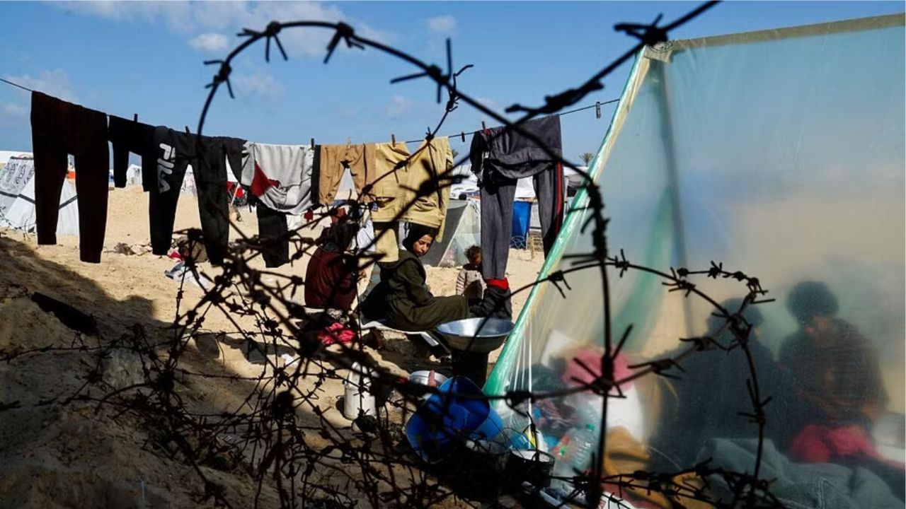 Displaced members of Palestinian Abu Mustafa family, who fled their house due to Israeli strikes, prepare food as they shelter at the border with Egypt, in Rafah in the southern Gaza Strip, February 10, 2024.