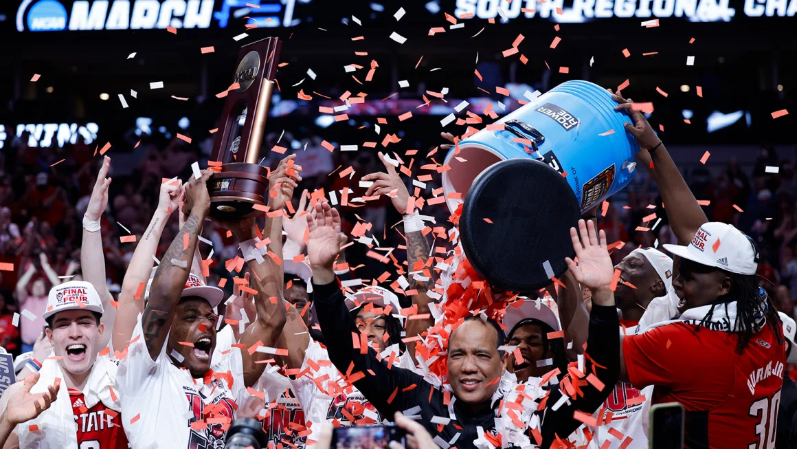 Head coach Kevin Keatts of the North Carolina State Wolfpack is doused with confetti as players celebrate their upset victory over Duke.